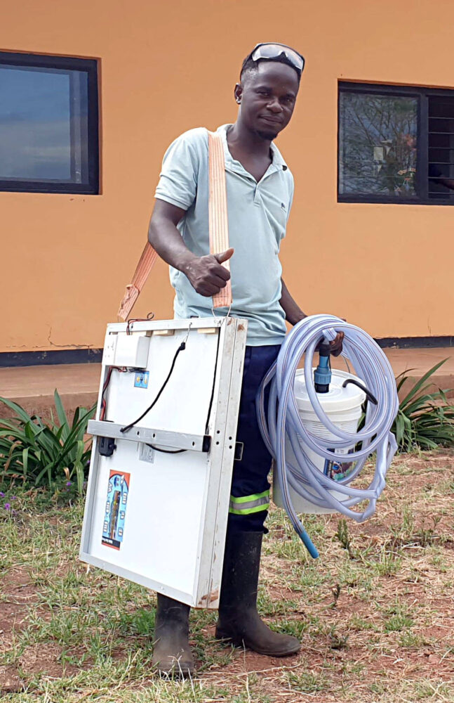Young man carrying Jacana portable irrigation pump